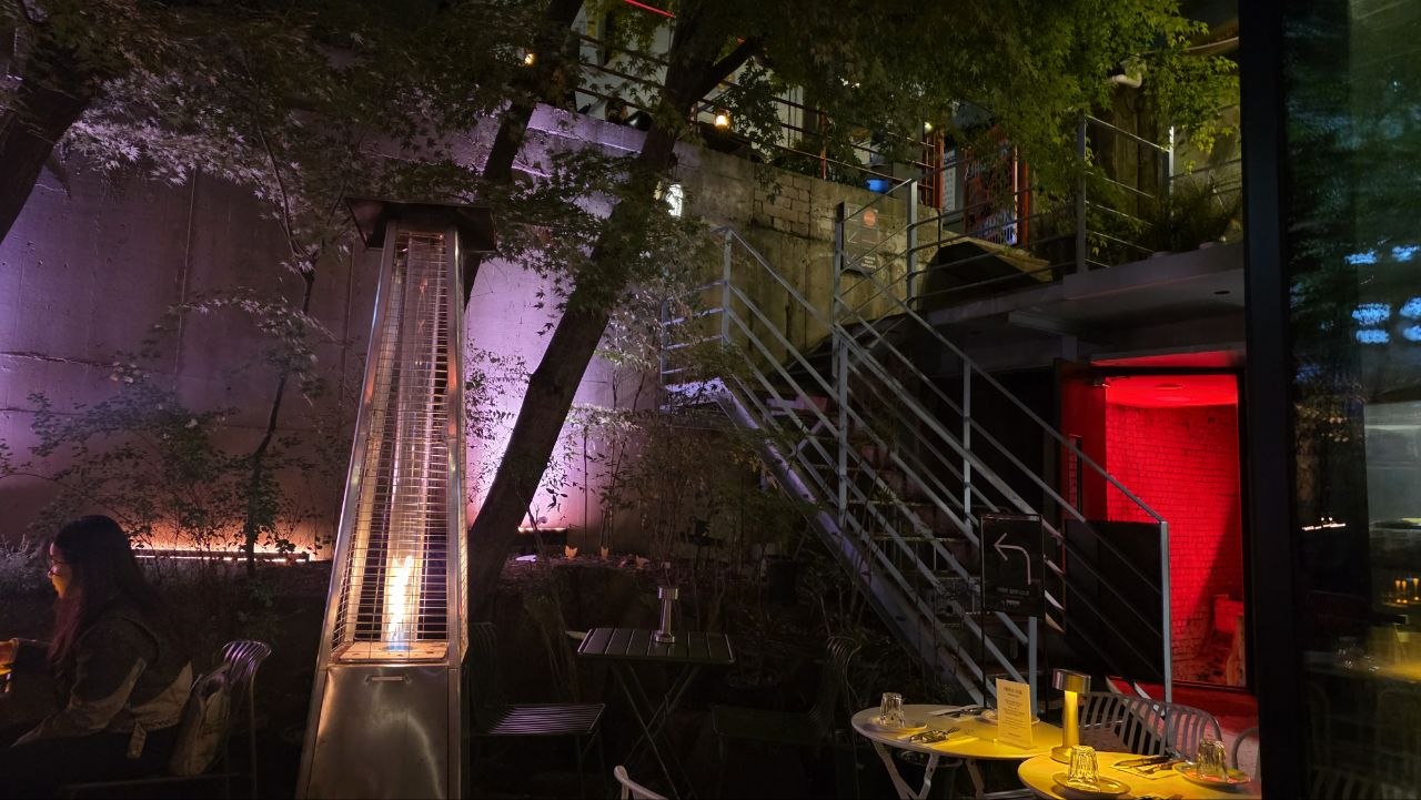 Raw concrete retaining wall lit in purple above the terrace